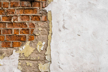 Cracked concrete vintage brick wall. Cracked putty on the wall and brick that looks through the...