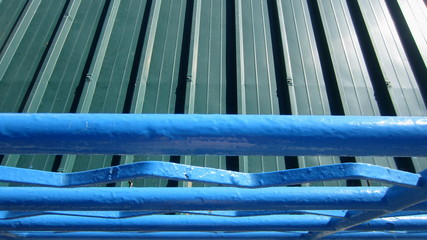 Blue metal railing over the green metal canopy. Urban elements up close.