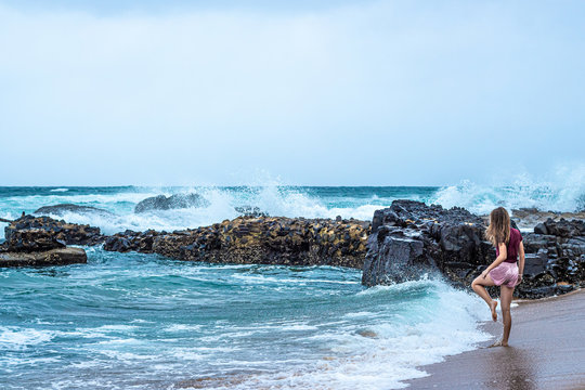 A young blonde girl watches the crashing waves along the Ballito coastline in South Africa