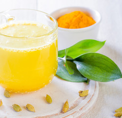 Cup with golden latte, turmeric and cardamom on white background