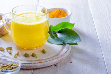 Cup with golden latte, turmeric and cardamom on white background