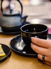 woman hand hold tea cup on table in cafe