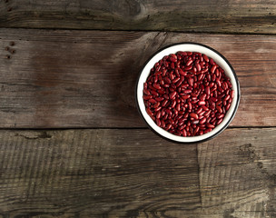 Obraz na płótnie Canvas raw oval red beans in a plate on a wooden table