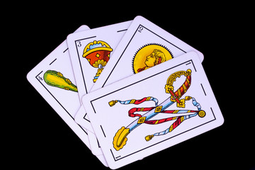 some cards from the spanish deck for playing cards games and gambling on a black background