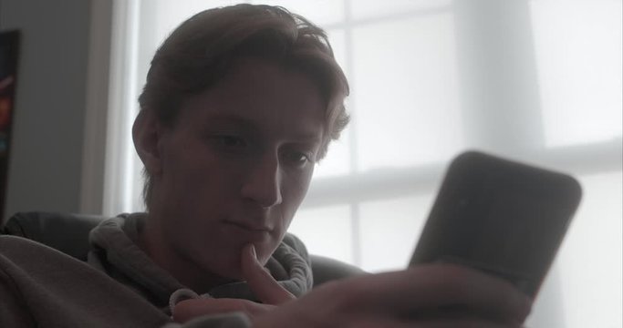 low angle teenage boy looks up from his phone