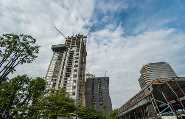 Fototapeta premium Construction site of building a high-rise building with a cranes against blue sky.