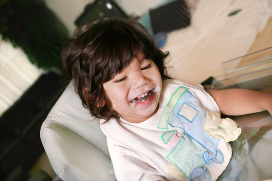 Biracial Disabled litle boy sitting in wheelchair smiling