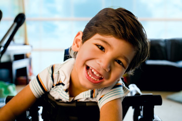 Happy smiling biracial disabled little boy standing in walker