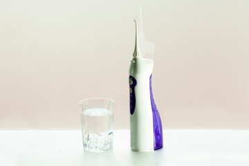 Oral care, irrigator and a glass of water are on the table in the bathroom