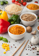 White bowl plates with boiled long grain basmati rice with vegetables and mushrooms on light table background with sticks and paprika pepper with corn,garlic and basil. Healthy vegan food.