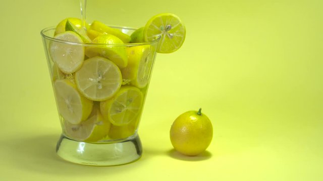  Original name(s): lemons in a glass on vibrant yellow backrgound.