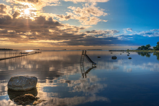 The morning in the border of Stangeskroken bay in the camping site of Landon village. The sun and clouds are reflecting in water surface. Jamtland, Sweden.