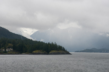 rainy and foggy mountain and forest view over coast and bay near Vancouver island , Canada