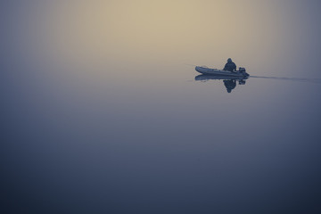 lonely fisherman on a boat in a very strong fog on the lake