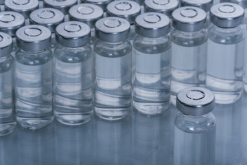 Glass medical ampoule vial for injection. Medicine is dry white drug penicillin powder or liquid with of aqueous solution in ampulla. Close up. Bottles ampule with aluminum cap on backgrounds gray.