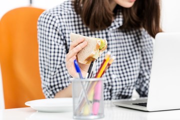 Portrait of businesswoman eating sandwich while working in her desk in office