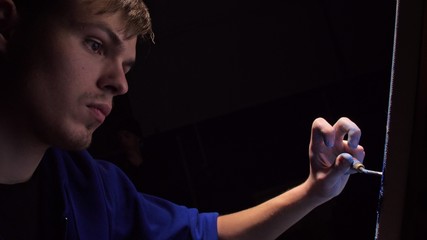 Artist copyist paint seascape with ship in ocean. Craftsman decorator draw as boat sail on blue sea with acrylic oil color. Draw finger, brush, knife palette. Indoor. Dark magic cinematic look.