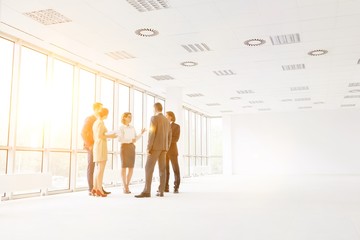 Business colleagues standing while discussing at new office