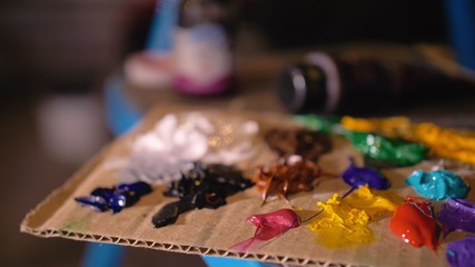 Artist designer draws an eagle on the wall. Craftsman decorator paints a picture with acrylic oil color brush. Close-up dark magic cinematic look. Painter dressed in a paint coat. Indoor.