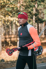 Training an athlete on the roller skaters. Biathlon ride on the roller skis with ski poles, in the helmet. Autumn workout. Roller sport. Adult man riding on skates.