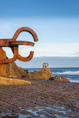 Fototapeta premium Widok zestawu rzeźb grzebienia wiatru, o wschodzie słońca z błękitnym niebem w pionie, w San Sebastian, Kraj Basków, Hiszpania