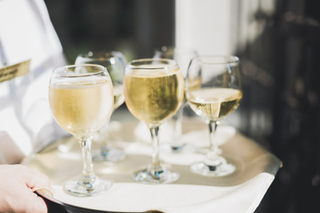 Waiter serving glasses with champagne on a tray