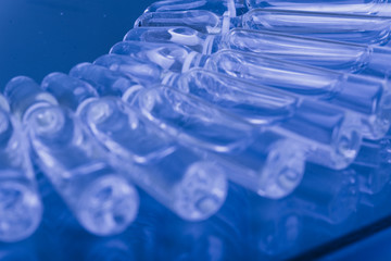 Glass medical ampoule vial for injection. Medicine is liquid sodium chloride with of aqueous solution in ampulla. Close up. Bottles ampule multicolor on background color and water. Human plasma.