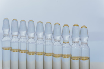 Glass medical ampoule vial for injection. Medicine is liquid sodium chloride with of aqueous solution in ampulla. Close up. Bottles ampule multicolor on background color and water. Human plasma.