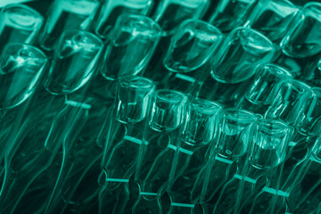 Glass medical ampoule vial for injection. Medicine is liquid sodium chloride with of aqueous solution in ampulla. Close up. Bottles ampule multicolor on background color and water. Human plasma.