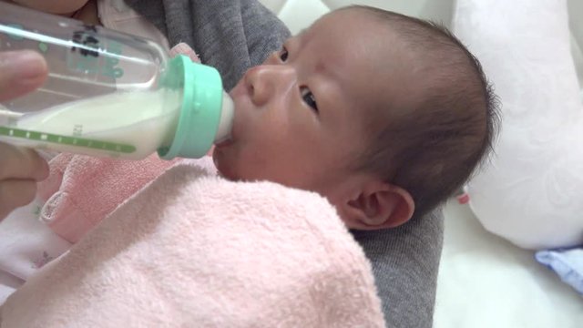 哺乳瓶でミルクを飲む新生児