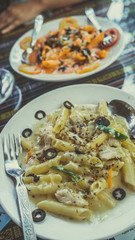 Yummy pasta on cafe table. Closeup plate with portion of tasty pasta with cream sauce placed on table in restaurant