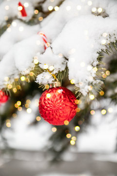 Merry Christmas and Happy Holidays greeting card or banner, decorated red toy ball and snow Christmas tree. New Year. Blurred bokeh background