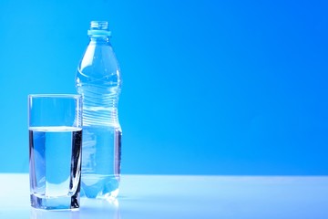 Bottle ang glass of water on blue background