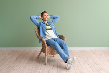 Handsome man sitting in armchair near color wall