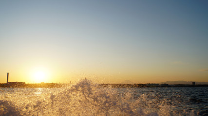 Obraz premium 波しぶきをオレンジに染める東京湾の夕日