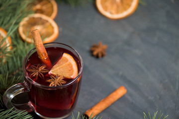 winter spicy alcoholic mulled wine based on red wine, spices and orange. on a dark background with fir branches, orange slices . close-up, space for text . the view from the top