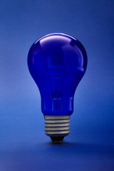 Light glass bulb on blue background. Close up.