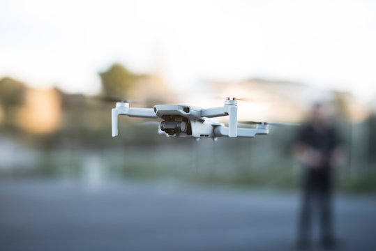 Man controlling drone in outdoors image with remote control and smartphone