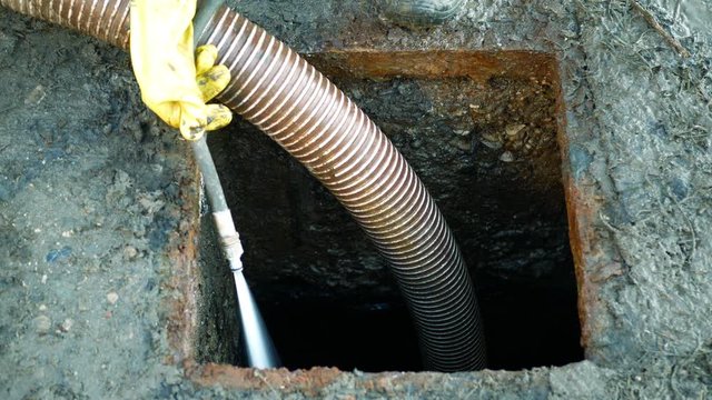 Septic cesspool emptying pumping into pipe tank by suction hose under high pressure. The sump contains pollution sludge sewage water black wastewater and faeces plus excrements from home
