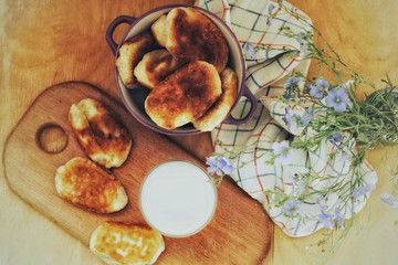 homemade pies and a glass of milk on a wooden board.