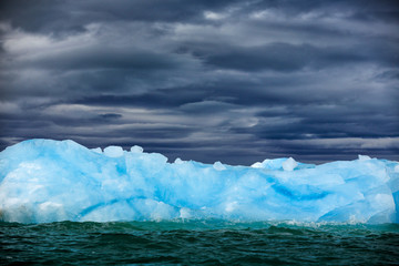 Obraz na płótnie Canvas Dark winter mountain with snow, blue glacier ice with sea in the foreground, Svalbard, Norway.