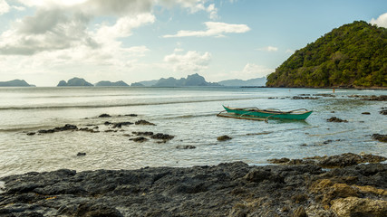 Green boat left on Las Cabanas beach, El Nido, Palawan, Philippines