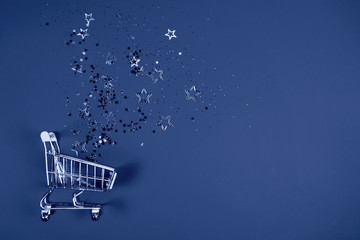 Shopping cart with confetti on blue background.