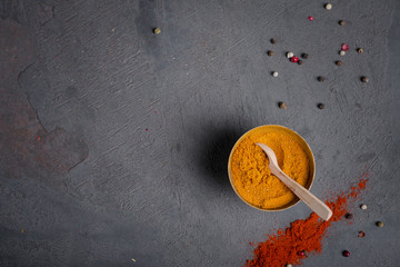 Loose curry spice in a metal bowl on a dark background and paprika with peppercorns