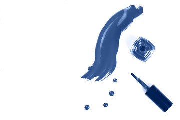 Classic blue nail polish drops and strokes as samples, bottle and brush isolated on white background with copy space for text. Beauty, fashion and woman lifestyle. Main color trend of the year 2020.