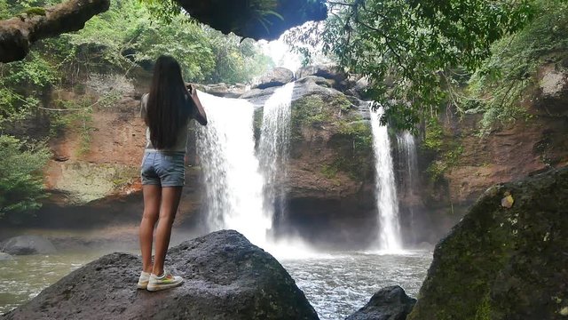 Woman taking pictures of a waterfall. Tourist woman