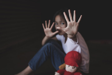 Little girl showing hand signaling to stop useful to campaign against violence and pain on dark background