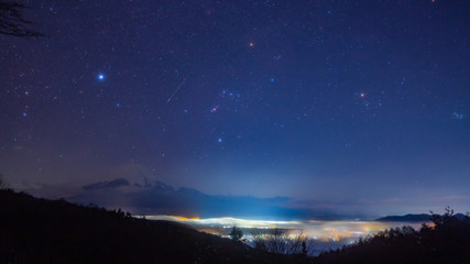 光る海に浮かぶ富士山と流れ星、オリオン座