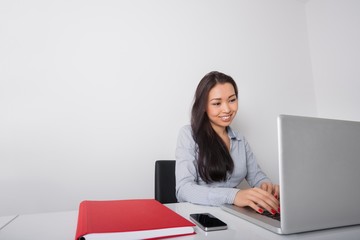 Happy young businesswoman using laptop at office desk