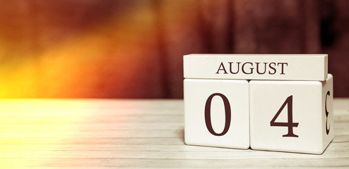 Calendar reminder event concept. Wooden cubes with numbers and month on August 4 with sunlight.